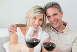 Couple holding out wine glasses at home