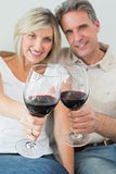 Happy couple holding out wine glasses