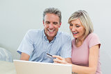Cheerful couple doing online shopping at home