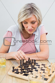 Concentrated woman playing chess at table