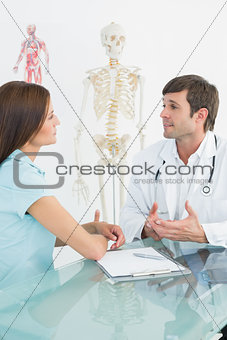 Male doctor listening to patient with concentration at desk