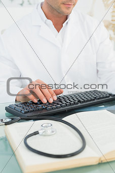 Mid section of a male doctor using computer