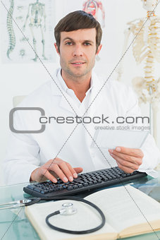 Portrait of a male doctor reading a note at desk