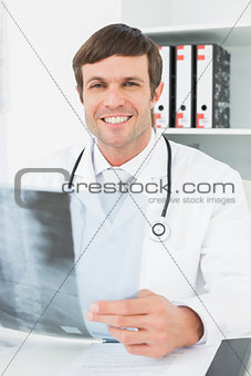 Smiling doctor with x-ray picture of spine in the medical office