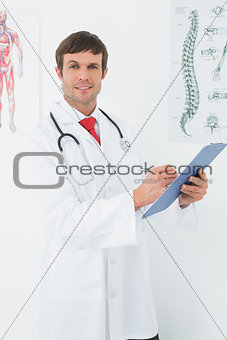 Male doctor holding clipboard in the medical office