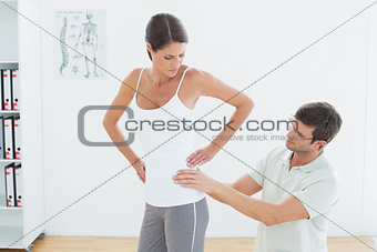 Physiotherapist examining woman's back in medical office