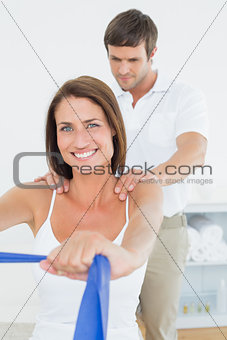 Male therapist assisting young woman with exercises