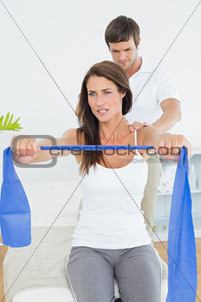 Male therapist assisting young woman with exercises