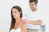Male chiropractor massaging a young woman's shoulder