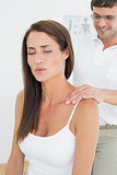 Male chiropractor massaging a young woman's shoulder