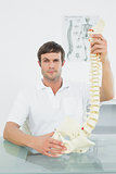 Confident male doctor holding skeleton model
