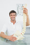 Smiling male doctor holding skeleton model