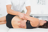 Physiotherapist massaging woman's back in medical office