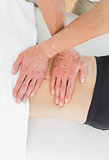 Mid section of a physiotherapist massaging woman's body