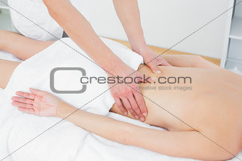 Mid section of a physiotherapist massaging woman's back