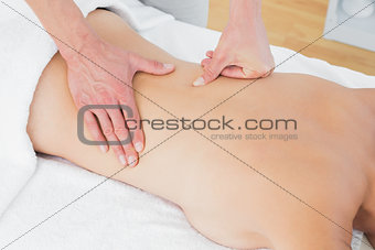 Mid section of a physiotherapist massaging woman's back