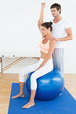 Woman on yoga ball while working with physical therapist
