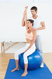 Woman on yoga ball working with physical therapist