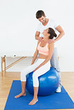 Woman on yoga ball working with physical therapist