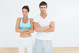 Fit young couple with arms crossed in fitness studio