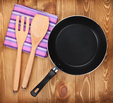 Frying pan and kitchen utensils on wooden table