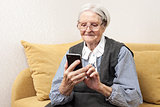 Senior woman using mobile phone while sitting on sofa