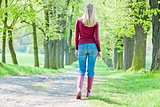 woman wearing rubber boots walking in spring alley