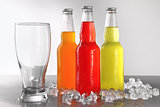 Three bottles with drinks with glass and ice
