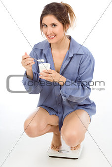 woman on weight scales eating Healthy yogurt