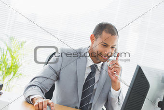 Businessman using computer and phone at office