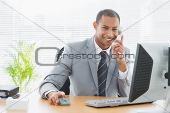 Businessman using computer and phone at office desk
