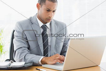 Concentrated businessman using laptop at office
