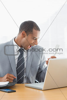Young businessman shouting into the phone at office