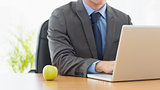 Smartly dressed businessman with laptop at office