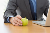 Smartly dressed businessman with laptop and apple at office