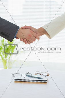 Closeup of shaking hands over eye glasses and diary