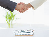 Shaking hands over eye glasses and diary after business meeting