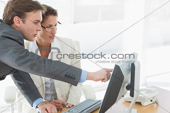 Business couple using computer at office desk