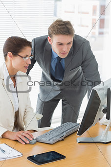 Business couple using computer at office desk