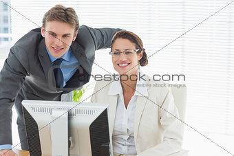 Confident smiling business couple with computer