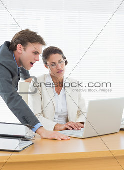 Business couple using laptop at office desk