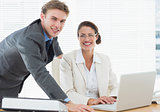 Confident smiling business couple with laptop