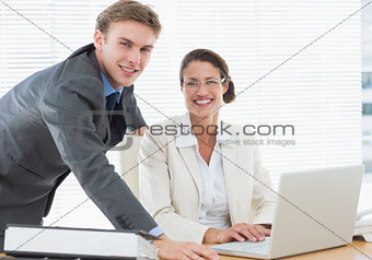 Confident smiling business couple with laptop