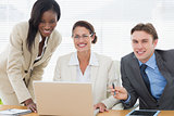 Smiling business colleagues with laptop in meeting