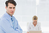 Serious businessman with woman working behind at office
