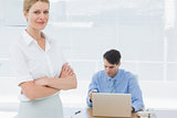 Smiling businesswoman with man working behind at office