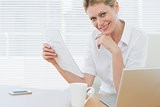 Businesswoman with laptop and document at desk