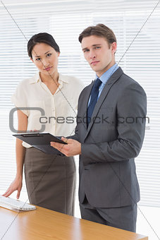 Confident business colleagues with clipboard at office
