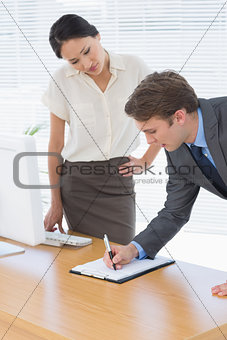 Colleagues with clipboard at office desk