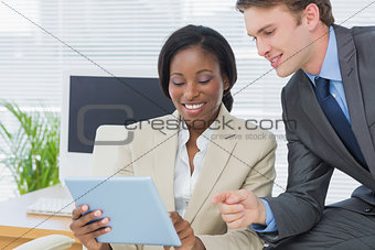 Colleagues using digital tablet in office